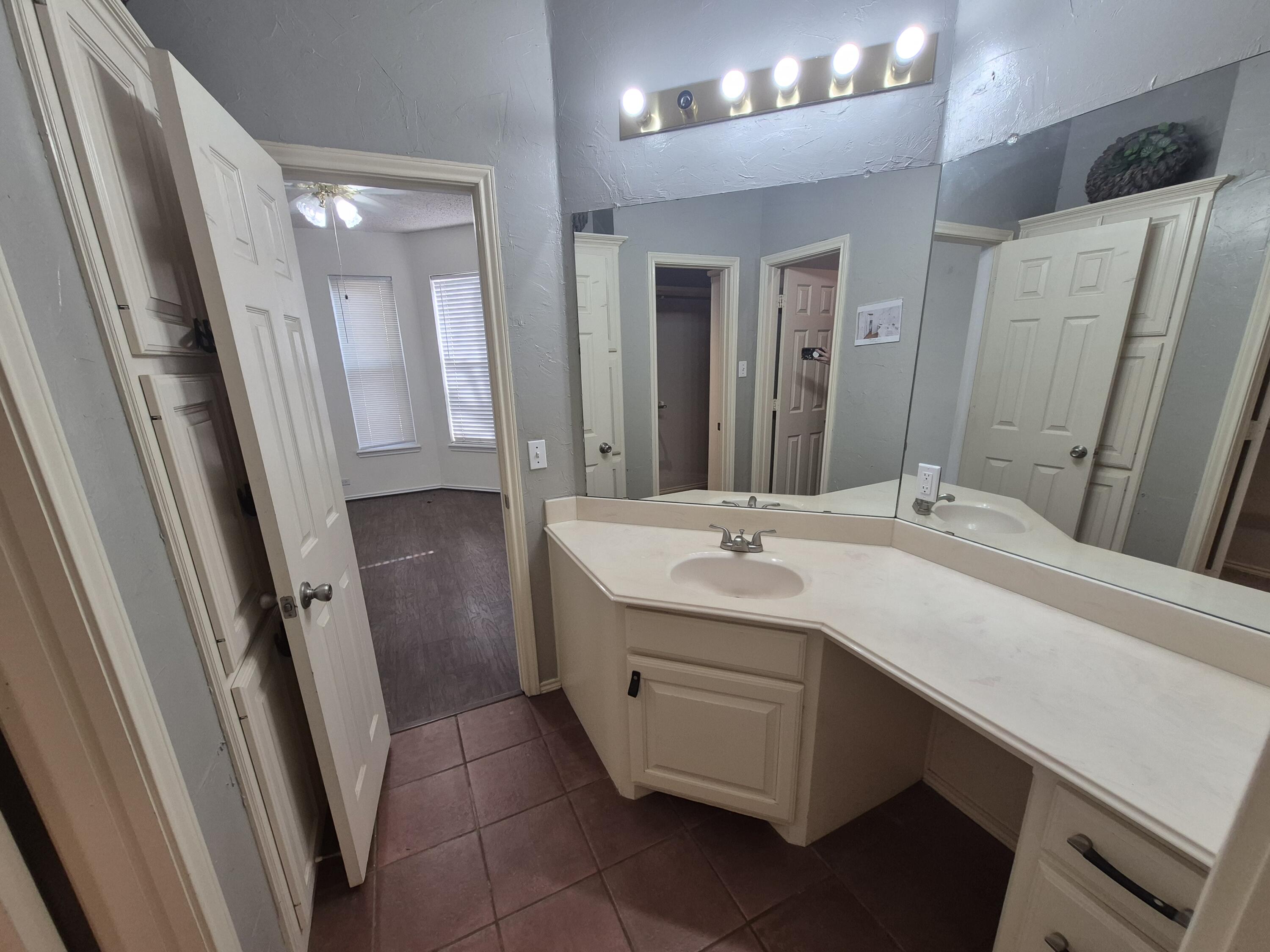 5117 79th Drive Lubbock, TX 79424 - Photo 16 of 35 a bathroom with a sink a mirror a vanity and a shower