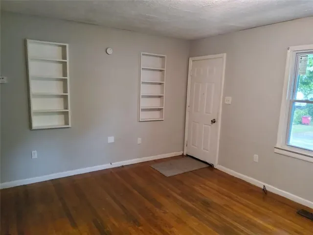 an empty room with wooden floor closet and windows
