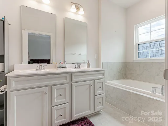 a bathroom with a bathtub a sink a vanity and a window