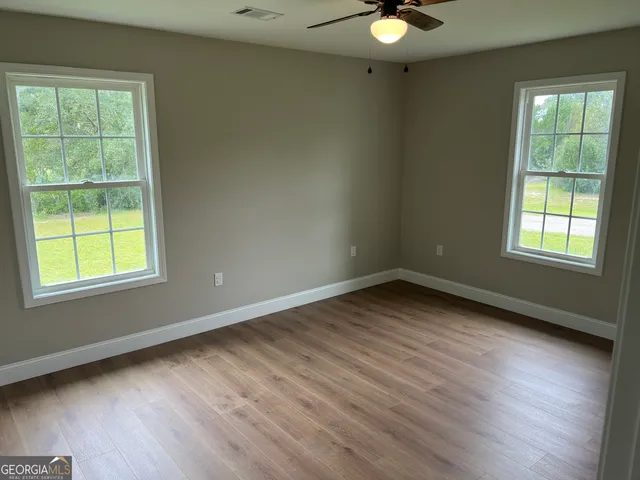 a view of an empty room and window and wooden floor