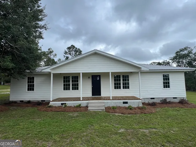a backyard of a house with potted plants and large tree