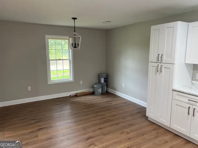 an empty room with wooden floor closet and windows