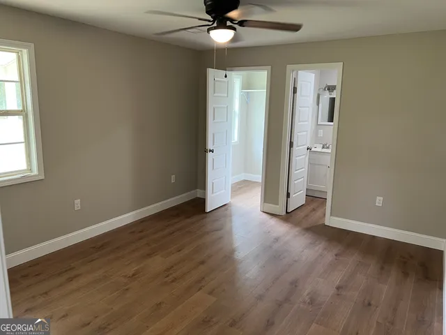 an empty room with wooden floor a ceiling fan and windows