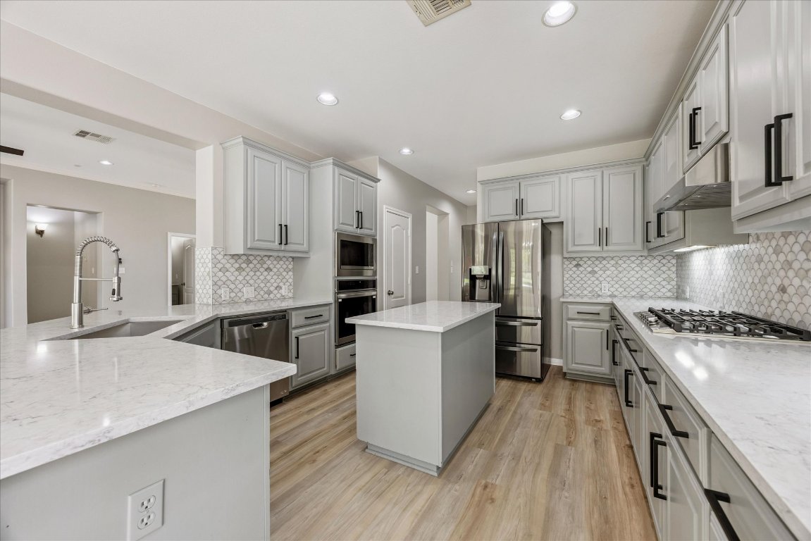 308 Calistoga Court Austin, TX 78732 - Photo 23 of 40 a kitchen with white cabinets and stainless steel appliances