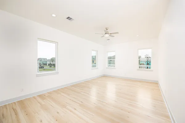 an empty room with wooden floor and windows