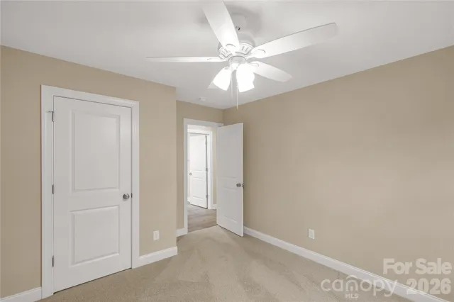a view of an empty room and chandelier fan