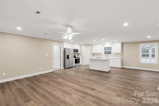 a view of a kitchen with a sink wooden cabinets and a window