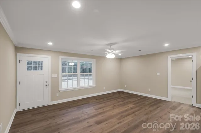 an empty room with wooden floor and windows