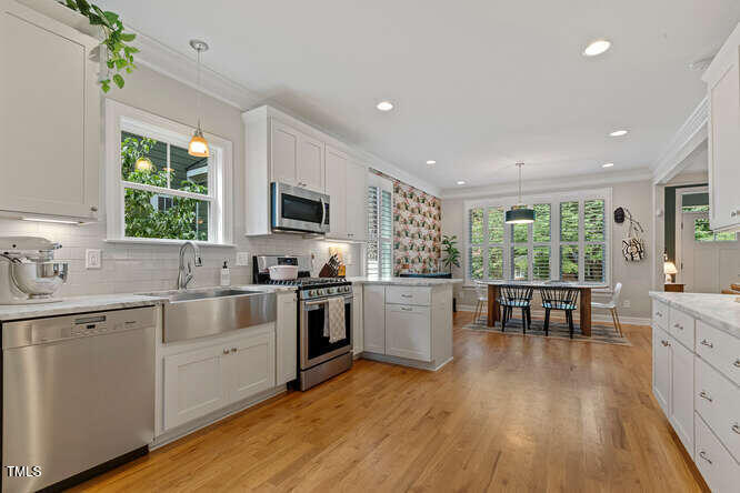 3012 Shenandoah Avenue Durham, NC 27704 - Photo 23 of 50 a kitchen with a sink wooden floor dining table and stainless steel appliances