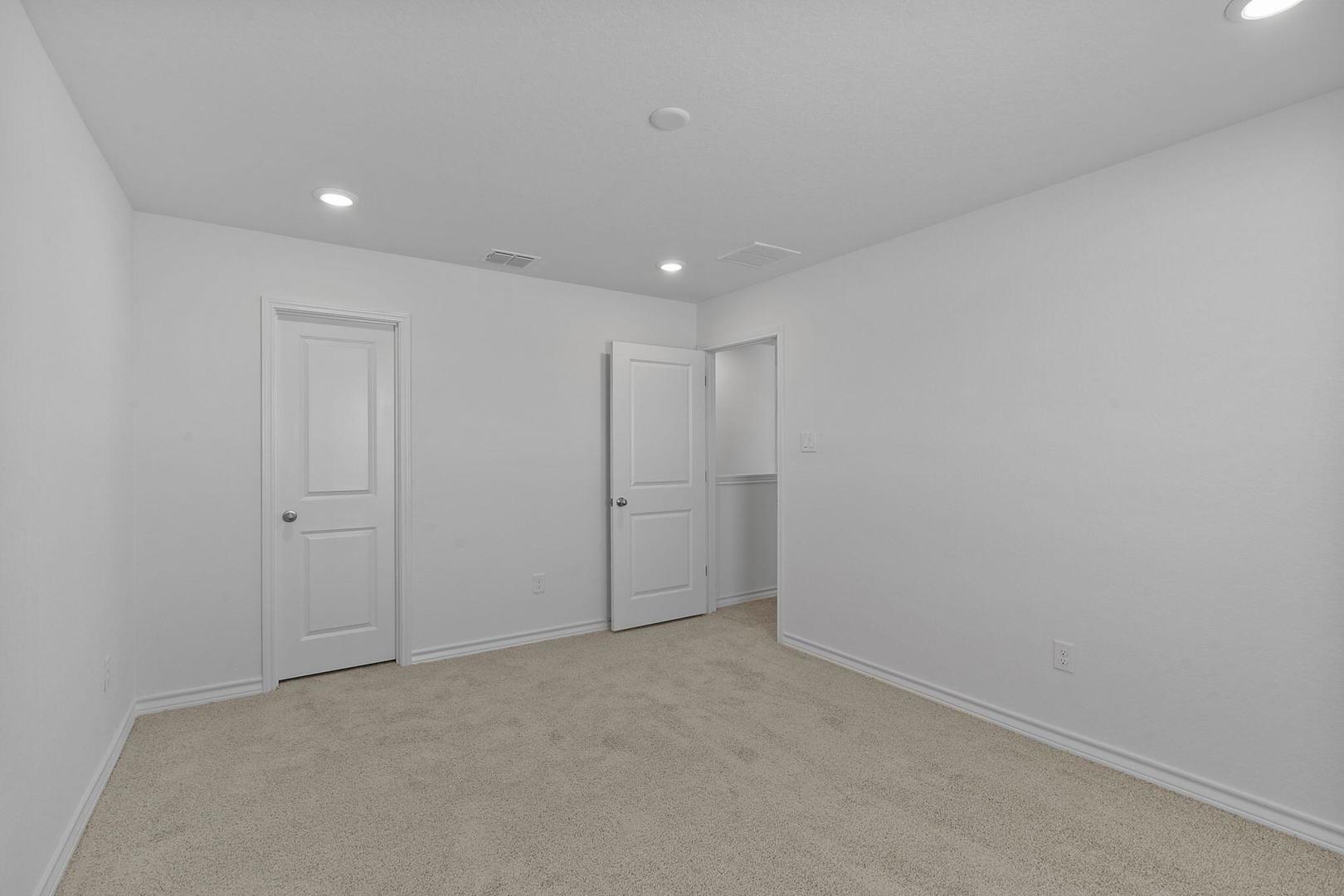 109 Hatari Trail Jarrell, TX 76537 - Photo 26 of 31 A well-lit bedroom features soft carpeting and two panel doors, one revealing a walk-in closet.