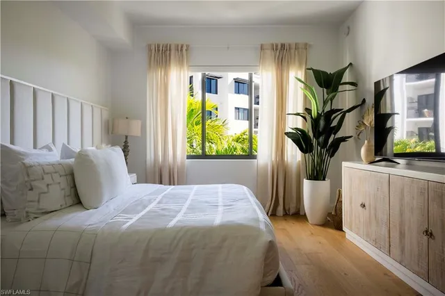 a bedroom with a large bed and a potted plant