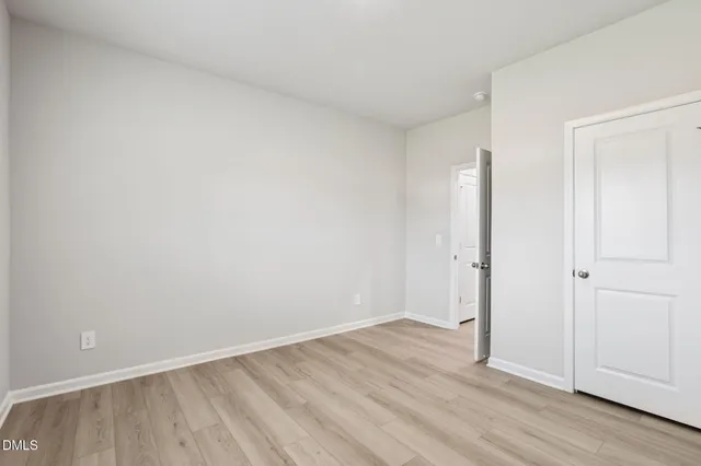 a view of an empty room with wooden floor and closet