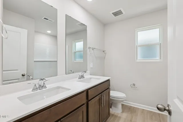 a bathroom with a toilet a sink a mirror and a shower