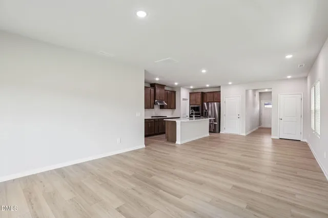 a large kitchen with hardwood floor a sink a window and stainless steel appliances