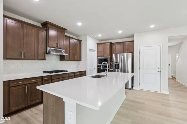 a kitchen with stainless steel appliances granite countertop a sink a stove and a refrigerator