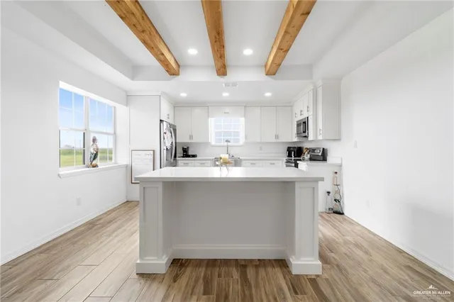 a kitchen with stainless steel appliances a sink a stove a refrigerator cabinets and a wooden floor