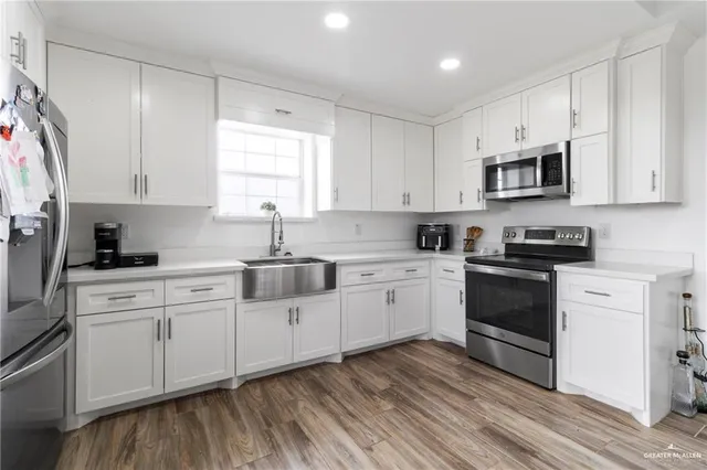 a kitchen with stainless steel appliances granite countertop a stove a sink and white cabinets