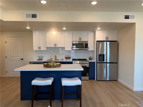 a kitchen with stainless steel appliances a table chairs refrigerator and microwave