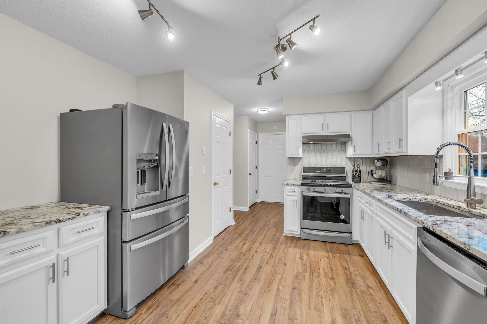 260 Pleasant Run Road Smyrna, TN 37167 - Photo 11 of 35 a kitchen with granite countertop a refrigerator oven a sink dishwasher and white cabinets with wooden floor