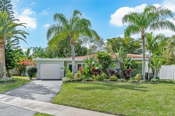 a view of a house with a yard and palm trees
