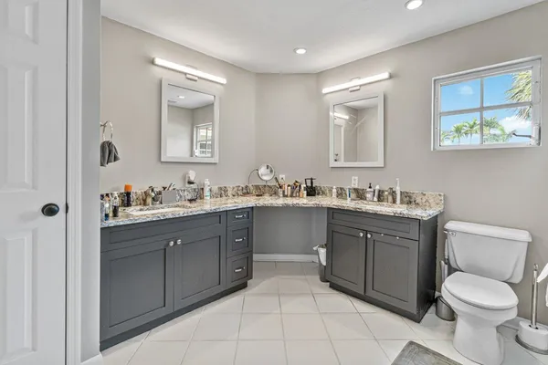 a bathroom with a toilet sink vanity granite and mirror