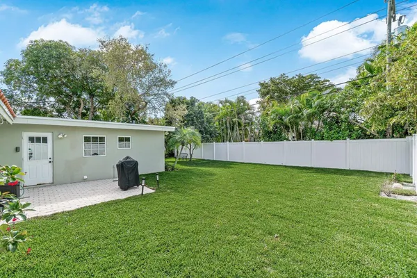 a backyard of a house with potted plants and a large tree