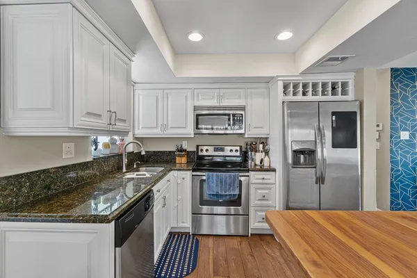 a kitchen with granite countertop a refrigerator stove and sink