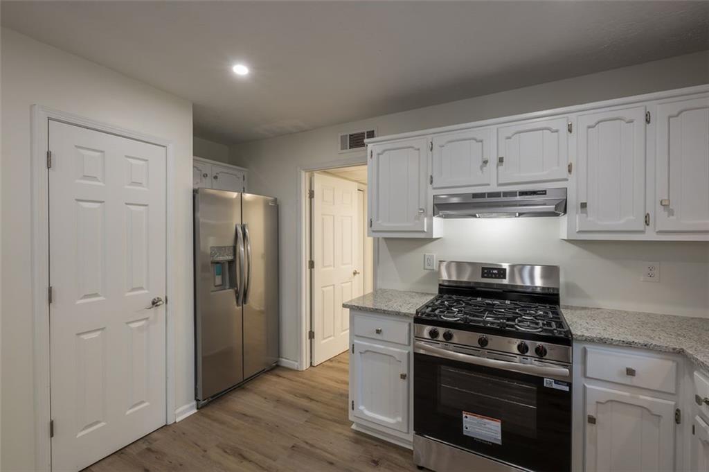 5081 Hubert Drive Powder Springs, GA 30127 - Photo 11 of 32 a kitchen with stainless steel appliances white cabinets and a stove top oven