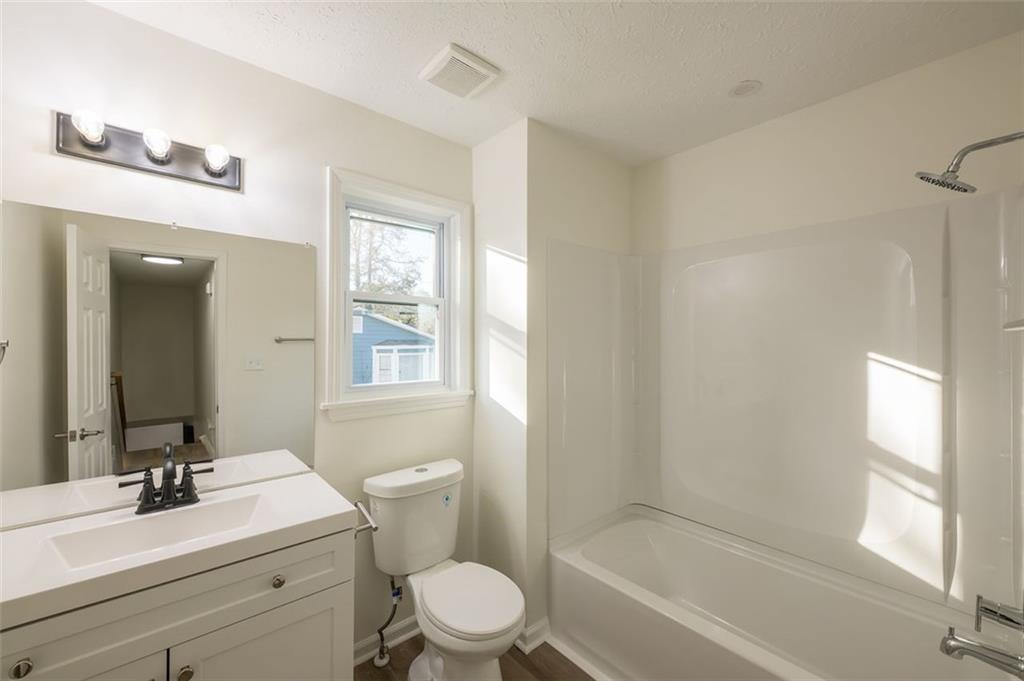 5081 Hubert Drive Powder Springs, GA 30127 - Photo 30 of 32 a bathroom with a toilet a sink a mirror a bathtub and vanity