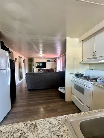 a kitchen with stainless steel appliances granite countertop a sink a stove a refrigerator a washer and dryer