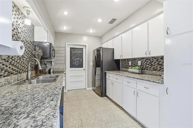 a kitchen with stainless steel appliances kitchen island granite countertop a sink stove and refrigerator