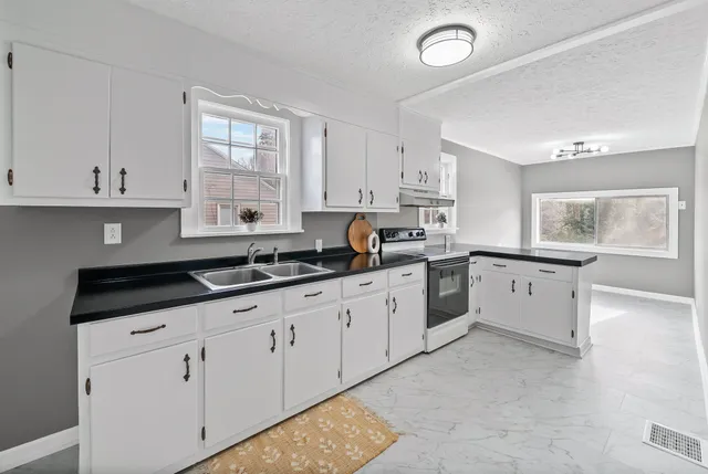 a kitchen with granite countertop white cabinets and stainless steel appliances