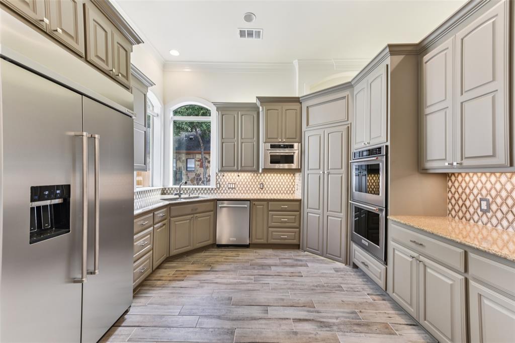 2203 Court Del Rey Round Rock, TX 78681 - Photo 9 of 35 Kitchen featuring appliances with stainless steel finishes, gray cabinetry, ornamental molding, light wood-type flooring, and backsplash