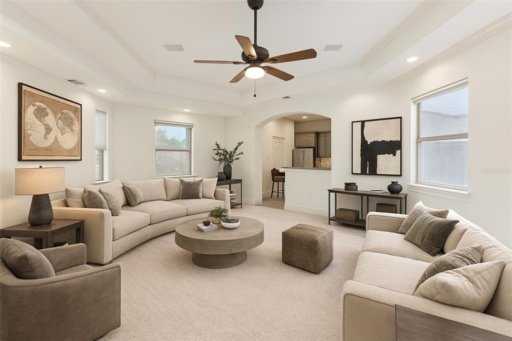 2203 Court Del Rey Round Rock, TX 78681 - Photo 26 of 35 Living area featuring arched walkways, carpet, a ceiling fan, a raised ceiling, and crown molding