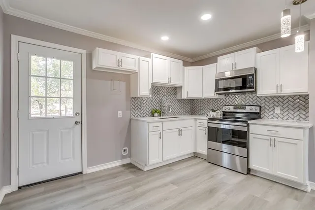a kitchen with granite countertop white cabinets and stainless steel appliances