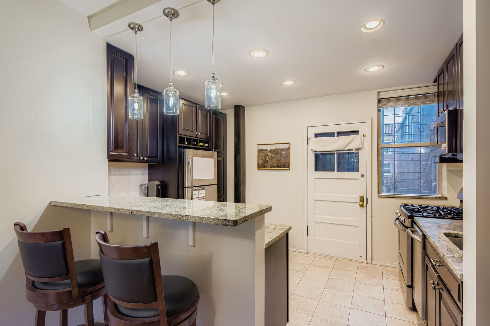 539 West Addison Street, Unit 2N Chicago, IL 60613 - Photo 14 of 23 a kitchen with stainless steel appliances kitchen island granite countertop a stove top oven a sink a dining table and chairs with wooden floor