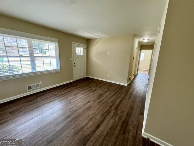 an empty room with wooden floor and windows