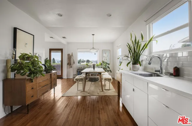 a kitchen with stainless steel appliances a sink dishwasher a refrigerator a stove and white cabinets with wooden floor