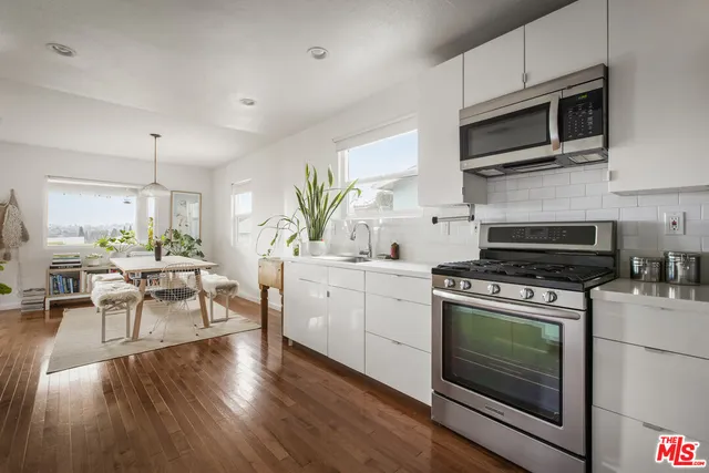 a kitchen with cabinets stainless steel appliances a sink and wooden floor