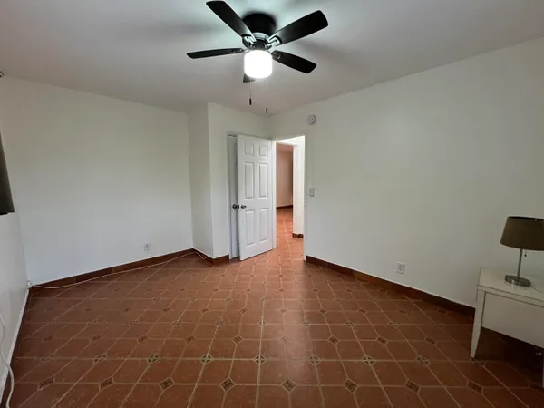 a view of an empty room with a ceiling fan and a rug