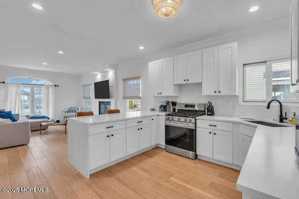 a large kitchen with stainless steel appliances granite countertop a stove top oven a sink dishwasher and white cabinets with wooden floor