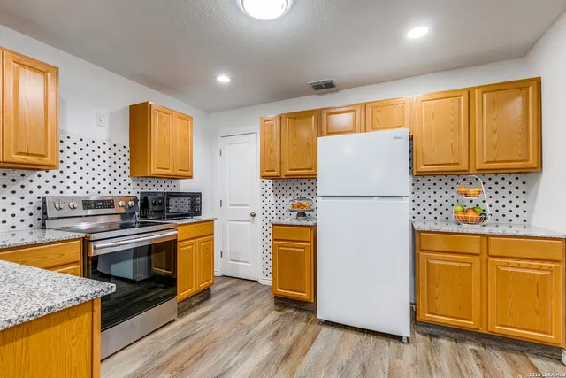 a kitchen with stainless steel appliances granite countertop a refrigerator a sink dishwasher a stove with wooden floor and cabinets