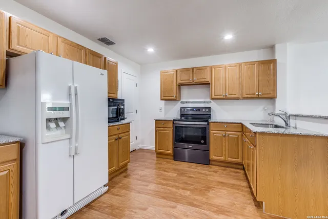 a kitchen with granite countertop a refrigerator stove top oven and sink