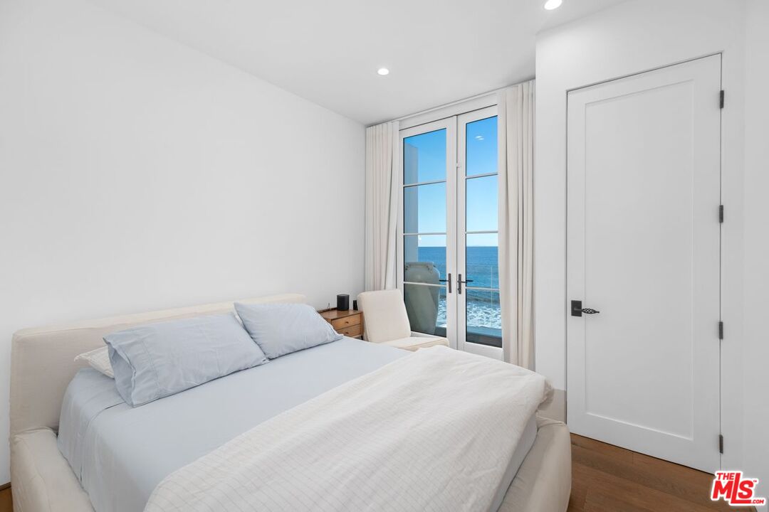 27212 Escondido Beach Road Malibu, CA 90265 - Photo 27 of 34 a bedroom with a large bed and wooden floor