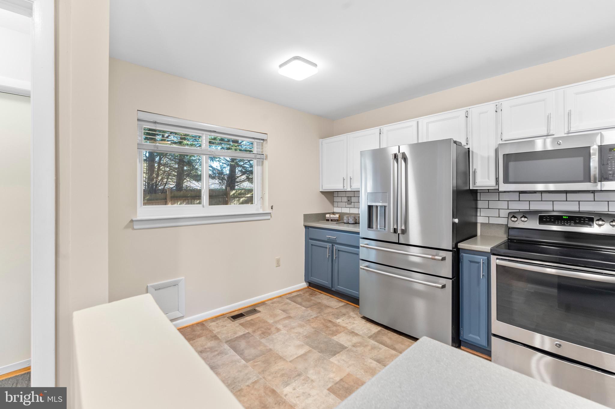 7512 Rolling Road Springfield, VA 22153 - Photo 11 of 32 a kitchen with granite countertop a refrigerator stove and microwave