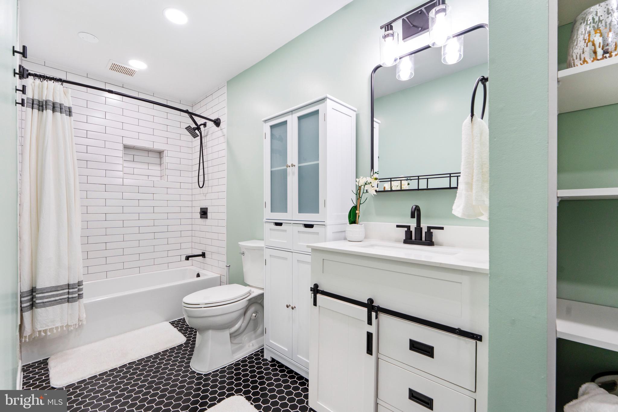 7512 Rolling Road Springfield, VA 22153 - Photo 16 of 32 a bathroom with a sink toilet a mirror and shower