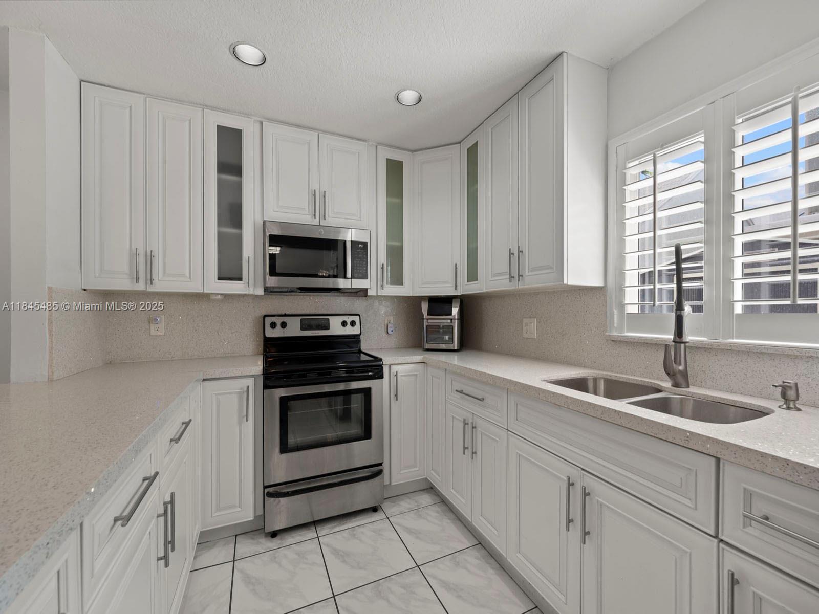 331 Northwest 101st Terrace Pembroke Pines, FL 33026 - Photo 17 of 42 a kitchen with white cabinets and a stove top oven