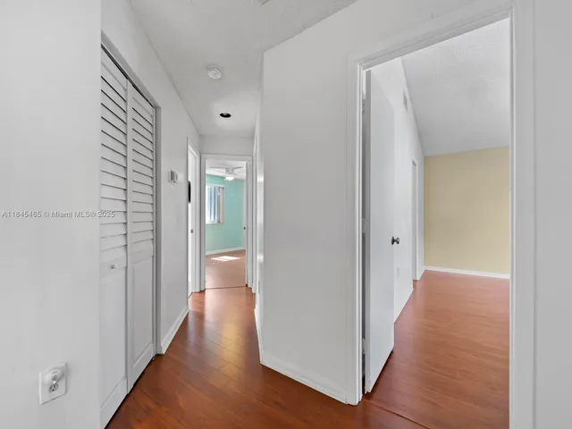an empty room with wooden floor chandelier fan and windows