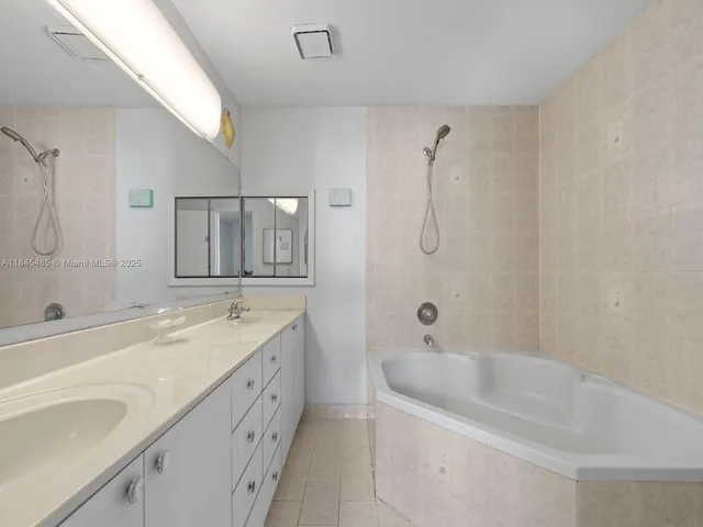 a bathroom with a double vanity sink a mirror and a bathtub