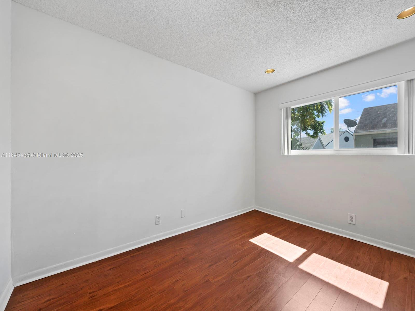 331 Northwest 101st Terrace Pembroke Pines, FL 33026 - Photo 35 of 42 an empty room with wooden floor and window